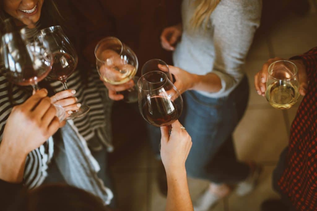 Des amis se regroupent autour d'un verre de vin. Cette image illustre la fonction "virements par SMS" de Ma French Bank.